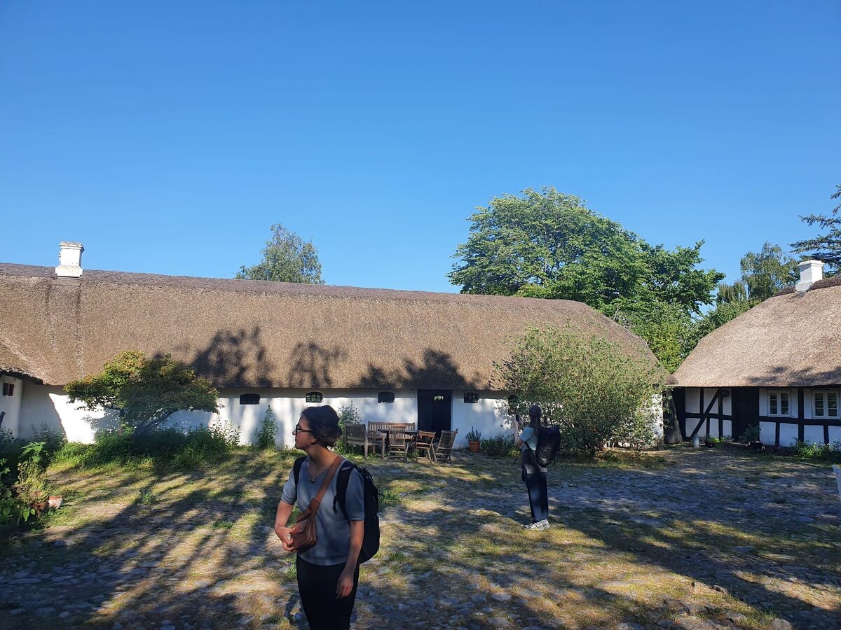 two visitors explore traditional housing in the sunshine in rural Denmark during IETM Aurhus