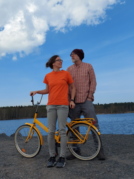 John and Tanja standing holding a bike in front of a river